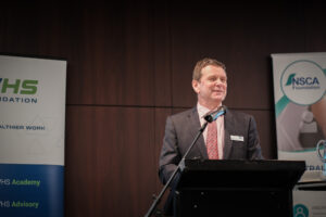 Bernie Doyle, Chairman of the NSCA Foundation is standing at a lectern presenting at the Perth Safety Forum