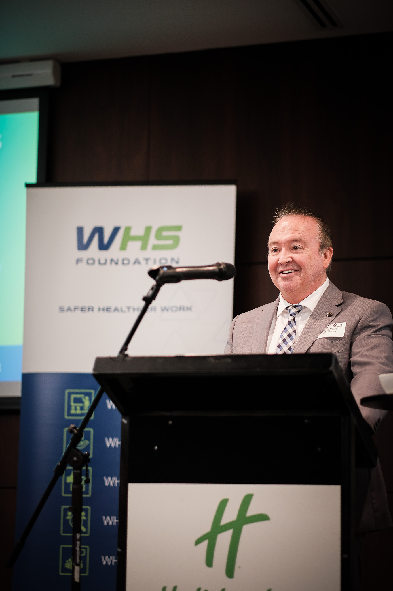 Michael Morgan, Managing Director, WHS Foundation is standing at a lectern presenting at the Perth Safety Forum