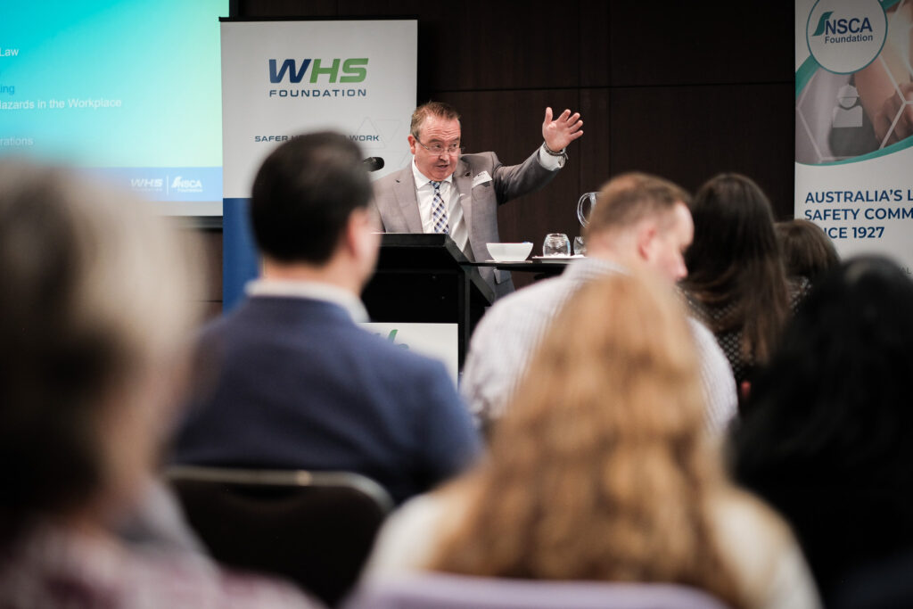 Michael Morgan, Managing Director, WHS Foundation is standing at a lectern presenting at the Perth Safety Forum